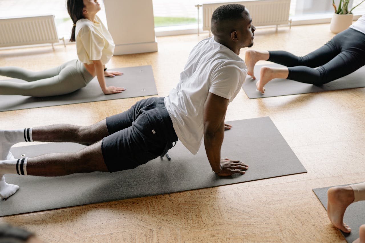 services-img Adults in a yoga class performing stretches on mats in a well-lit studio.